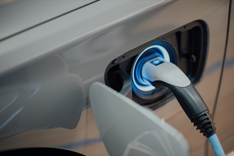 Enchufe de recarga conectado a coche eléctrico con anillo LED azul